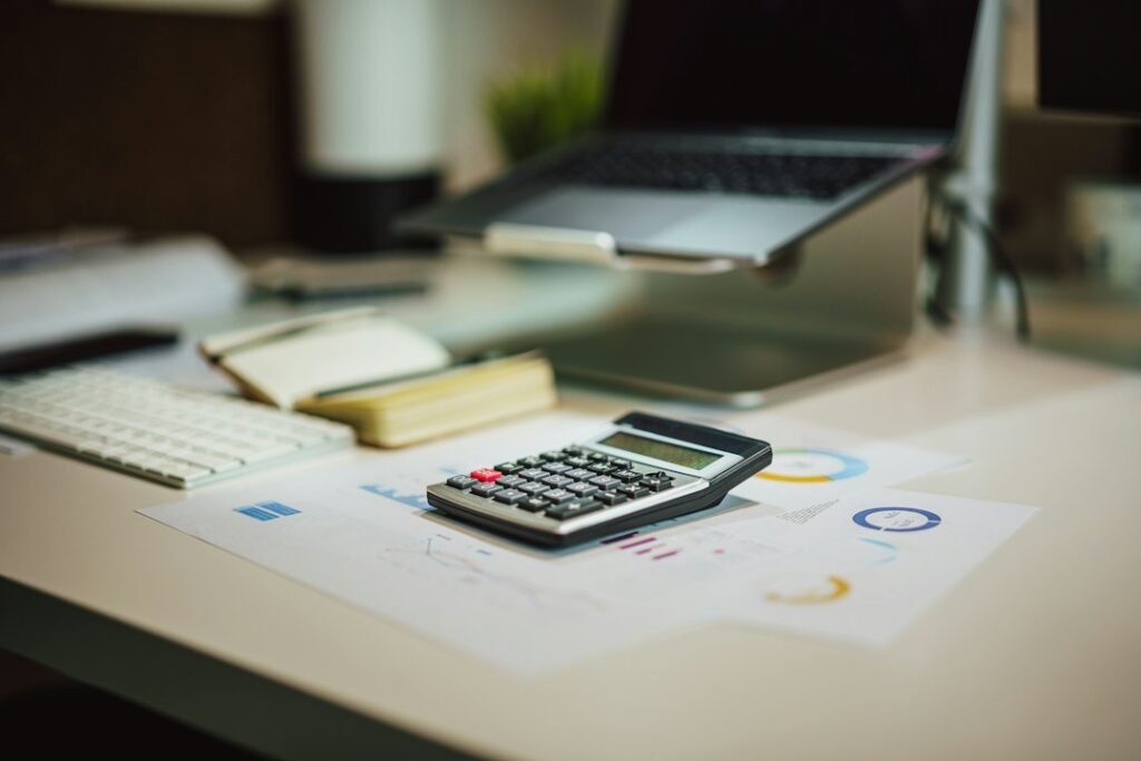 Calculadora junto a un portátil sobre una mesa, para preparar la declaración de la Renta con acciones y fondos