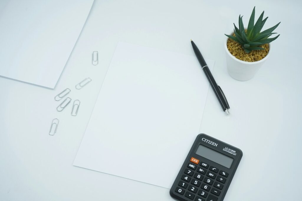 Calculadora negra junto a un bolígrafo sobre papel, para distinguir la base imponible general y la del ahorro