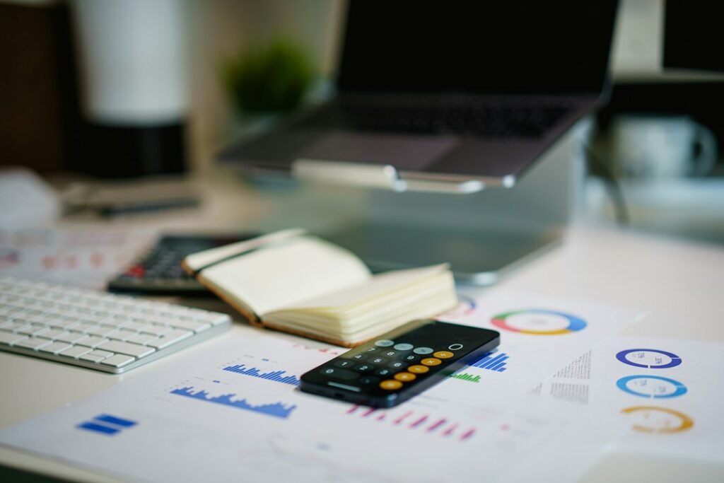 Escritorio con móvil y gráficos financieros, para importar datos fiscales del bróker a Renta Web