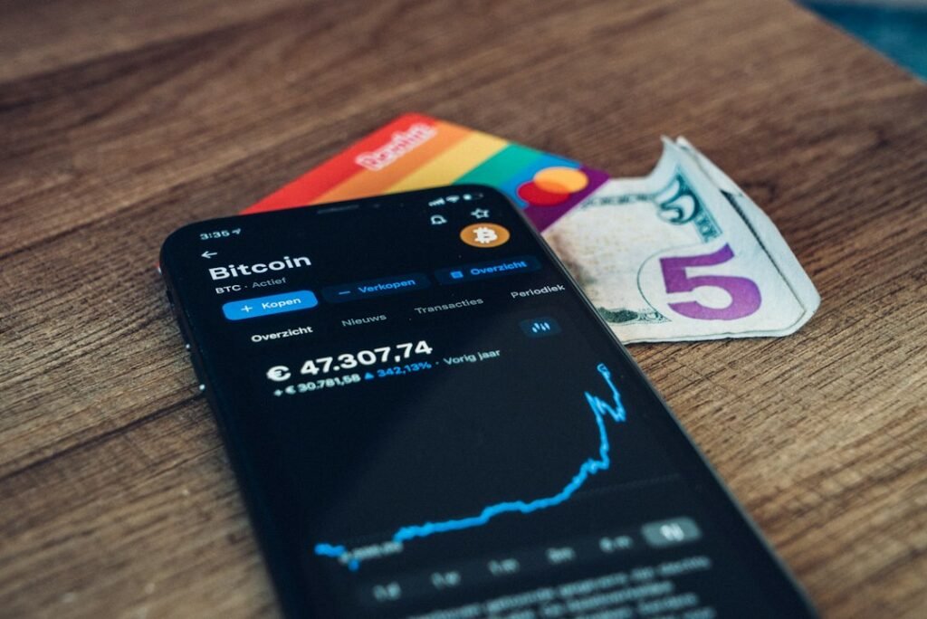 Móvil con app de criptomonedas sobre madera, wallets frías y cold wallets