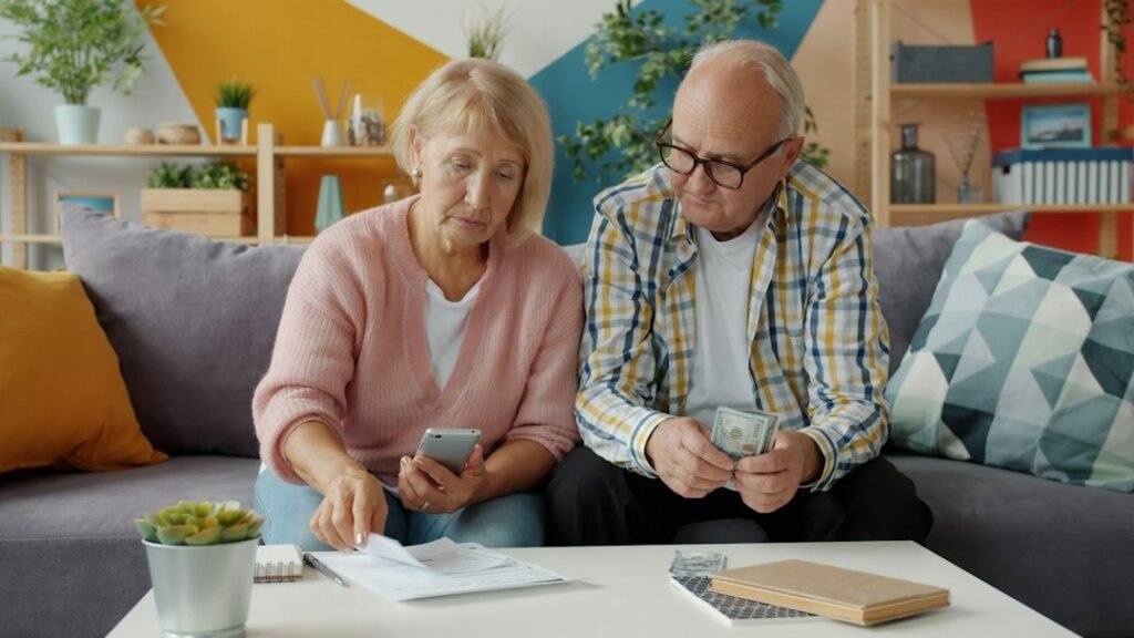 Pareja mayor revisando facturas y el teléfono, rescatar un plan de pensiones