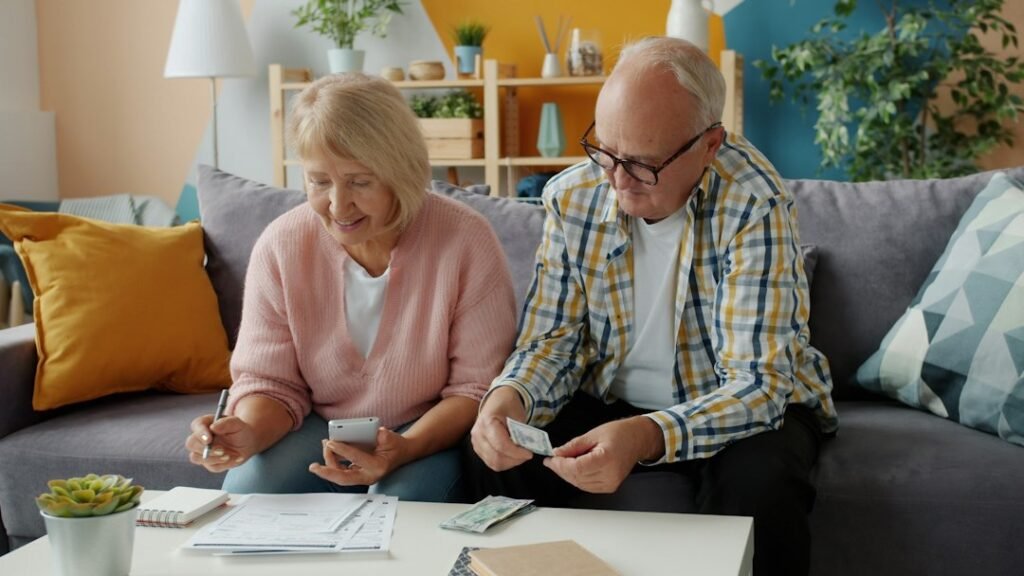 Pareja mayor revisando sus finanzas en el sofá, fiscalidad de los planes de pensiones