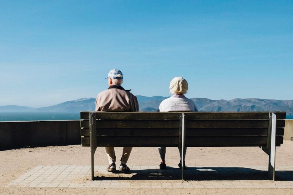 Pareja sentada en un banco frente al mar, comparativa PIAS vs planes de pensiones