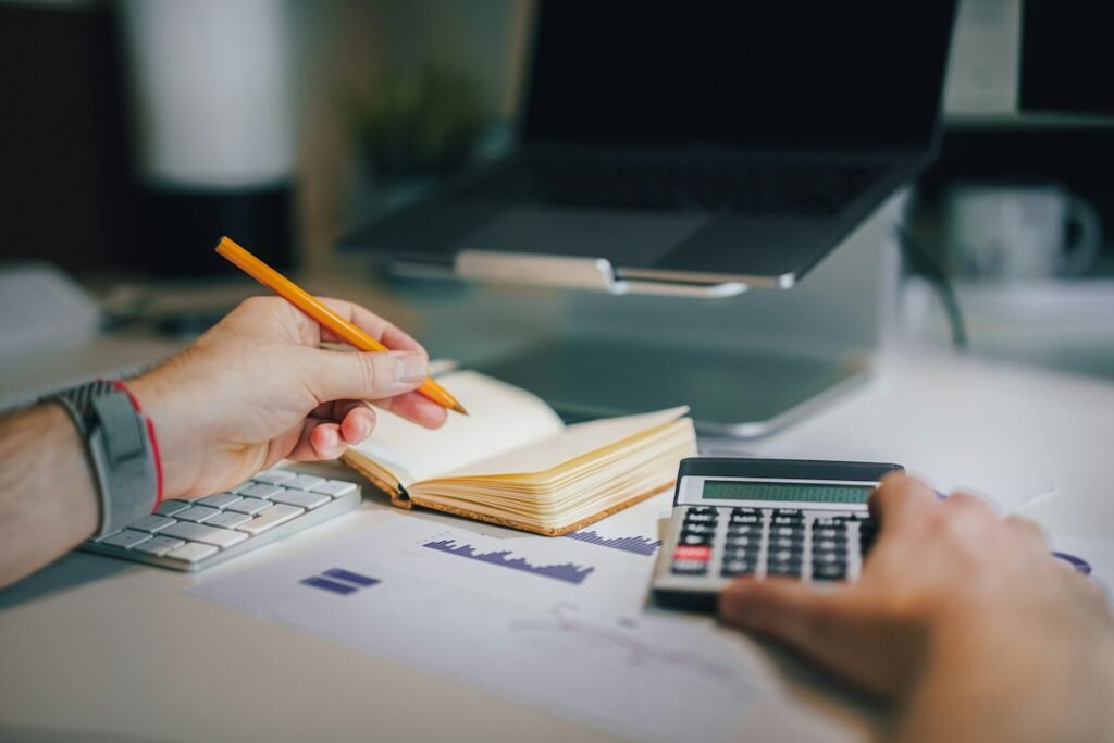 Persona en un escritorio con calculadora y cuaderno, localizando las casillas de Renta Web para inversiones