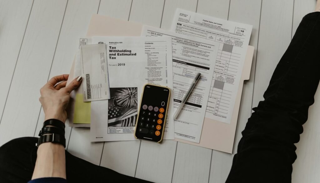 Persona sosteniendo un papel junto a un bolígrafo y una calculadora, para rectificar la Renta